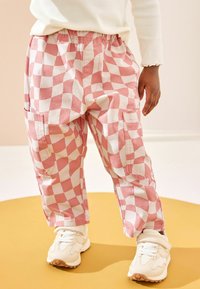 Rosa och vita rutiga cargobyxor med elastiskt midjeband, med fickor och en avslappnad passform, kombinerat med ljusa sneakers.