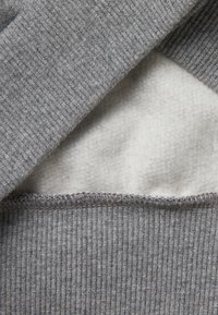 Materiale del sudario grigio con un esterno a coste testurizzato. Fodera interna in morbido pile bianco. Bordo finito con dettagli di cucitura.