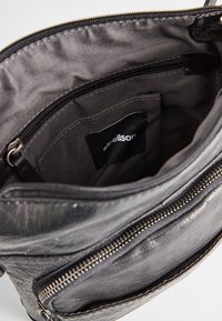 Borsa in pelle nera con compartimento principale aperto che mostra la tasca interna con zip e l'etichetta del marchio Strellson nella fodera interna.