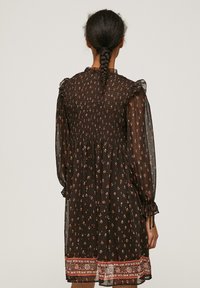 Rochie lungă, neagră, din material transparent, cu mâneci lungi și modele florale în roșu, galben și alb. Prezintă un corp smockat și detalii decorative la tiv.