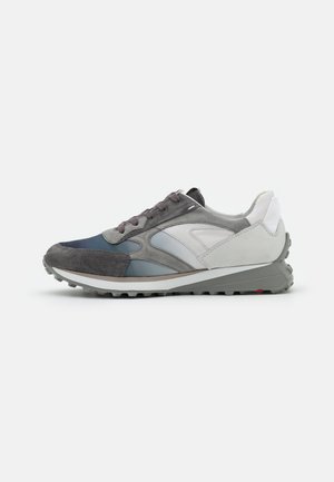 Gray and navy athletic shoe featuring a mix of suede and smooth materials, prominent laces, and a textured rubber sole with a slight heel.