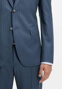 Granatowa marynarka w prążek, z dwoma guzikami, klapami z wcięciem oraz pojedynczą kieszenią na piersi. Tkanina ma gładką teksturę z delikatnym połyskiem.