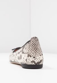 Flat shoes with a black and white snake print texture, rounded toe, low heel, and a decorative bow on the front.
