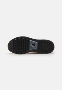 Semelle extérieure noire en caoutchouc d'une chaussure Nike Air montrant le motif de la bande de roulement, les sections de grip surélevées et un logo Nike visible au niveau du médio-pied.