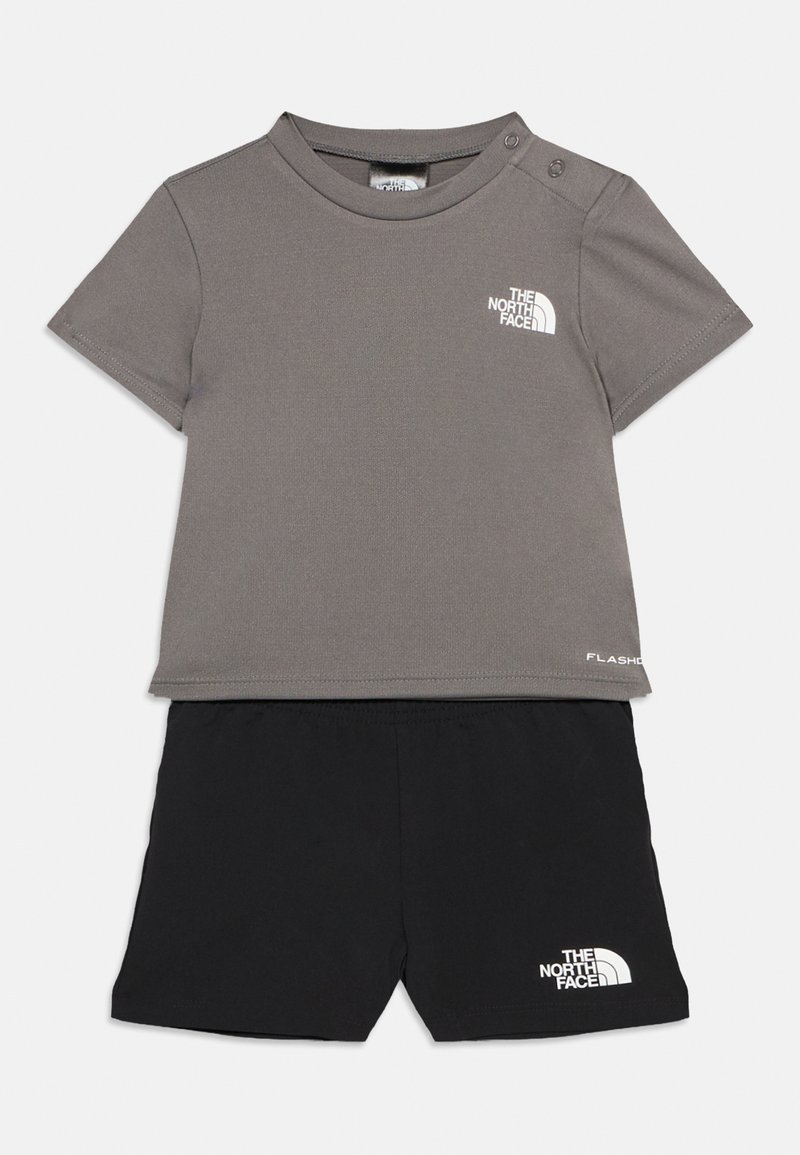 Γκρι κοντομάνικο πουκάμισο με κουμπιά στους ώμους και μαύρο σορτς, και τα δύο με το λογότυπο The North Face, απλωμένα επίπεδα σε λευκό φόντο.