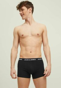 Caleçons noirs en tissu doux avec une taille confortable arborant le logo "JACK & JONES" en blanc. Modèle présenté sans chemise.