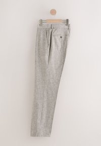 Világosszürke nadrág egy fa vállfán, texturált anyaggal, két oldalzsebbel és egy gombbal záródó hátsó zsebbel.