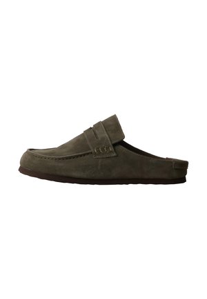 Olive green suede slip-on loafer with low heel and decorative strap detail on top, shown from the side on a white background.