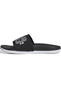 Black slide sandals with a textured strap and large silver logo. White outsole with a smooth finish. Casual design for comfort.