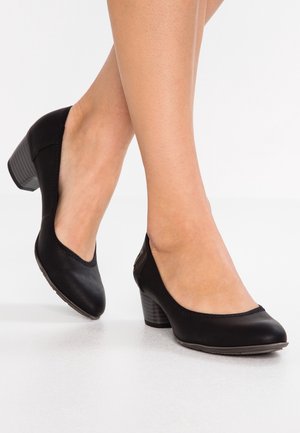 Chaussures à talons en cuir noir avec un bout rond, présentant des accents cousus et un talon bloc texturé. Surface lisse et design minimaliste.