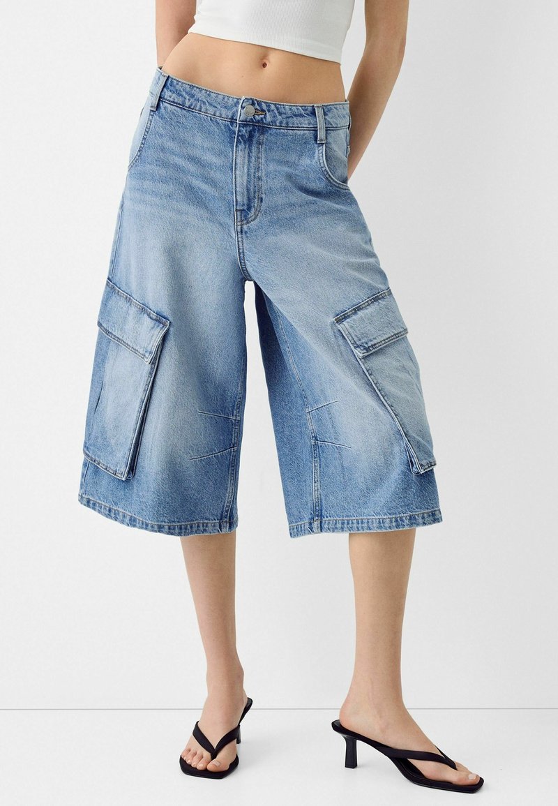 Farkkutyyppiset cargo-shortsit, vaaleansinisiä, haalistuneella pesulla, leveillä lahkeilla, kahdella isoilla sivutaskulla ja klassisella vyötäröllä. Sileä pinta.