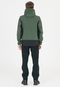 Tvåfärgad jacka i grönt och svart, med huva och dragkedja. Matchad med svarta byxor; slät textur och slim fit-design.