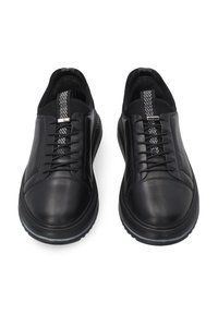 Schwarze Lederschuhe mit abgerundetem Zehenbereich, strukturierten Akzenten und einem gemusterten Schnürbereich sowie einer Zuglasche an der Ferse. Gummisohle.