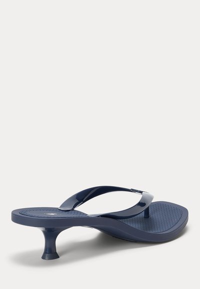 Marineblå trusesandal med teksturert fotseng og lav buet kattehæl, vist fra siden på ensfarget bakgrunn.