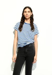 Blue and white striped short-sleeve t-shirt with rolled cuffs, paired with high-waisted black jeans. The fabric appears soft and casual.