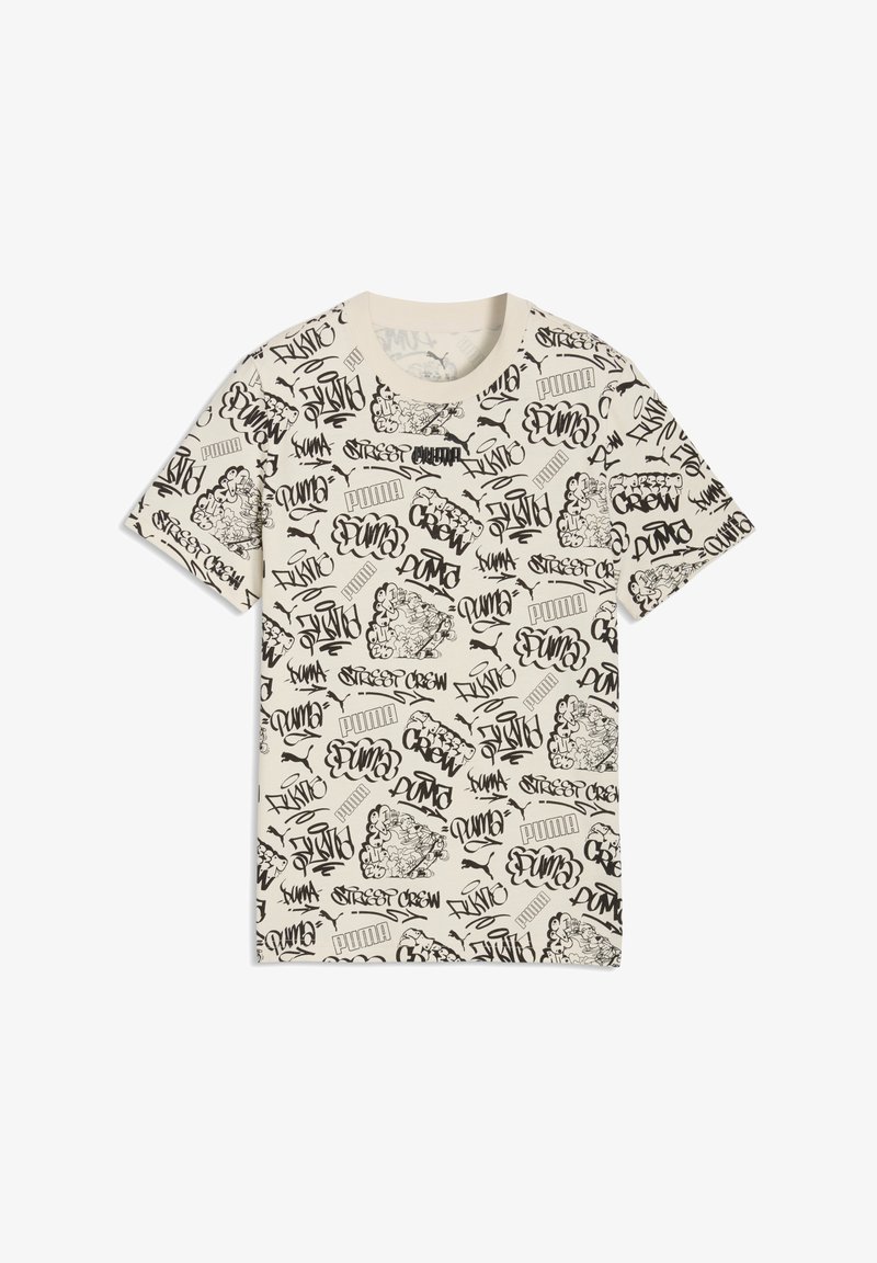 T-shirt à manches courtes crème avec texte en style graffiti noir et croquis, comprenant des logos "Puma" répétés et des motifs d'art de rue.