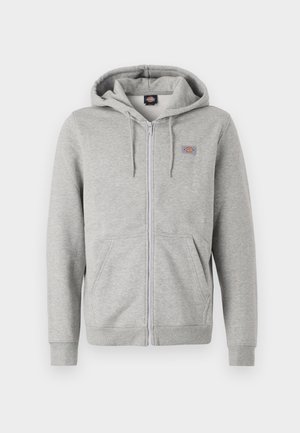 Graue Kapuzenjacke mit Reißverschluss aus einem weichen Baumwollmix. Besitzt eine Kordelzugkapuze, zwei Vordertaschen und ein kleines Logo auf der Brust.