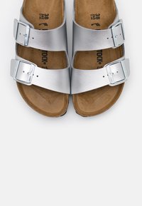 Sølvrødde sandaler med to justerbare stropper, metalspenner og en brun korkfotbed, med et flatt, åpent design. Størrelse 38.