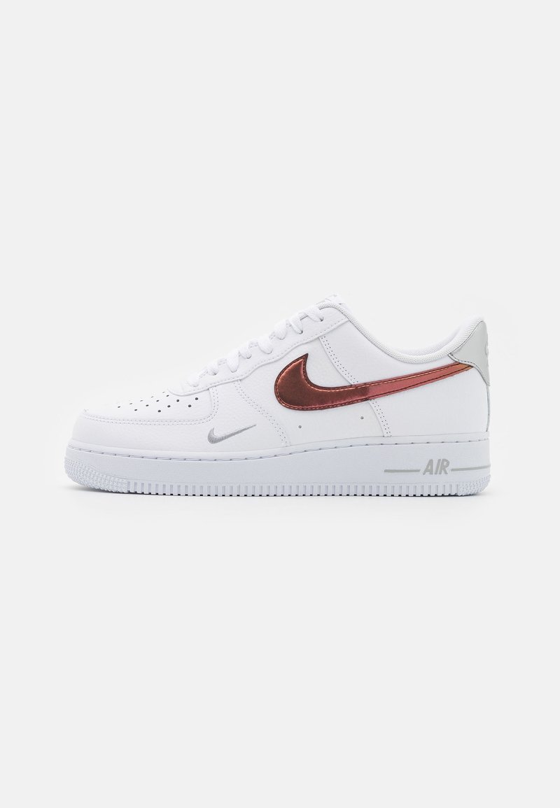 Vita Nike Air Force 1-sneakers med en slät läderövre del, med en metallisk kopparswoosh, silverdetaljer och en texturerad gummisula.
