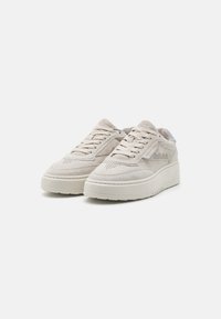 Beige Wildlederschuhe mit strukturierter Oberfläche, ausgestattet mit einer dicken weißen Plateausohle, Schnürdesign und perforierten Akzenten an den Seiten.
