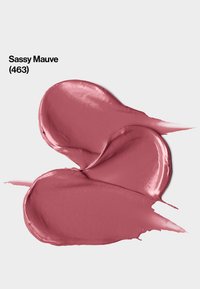 Échantillon de crème maquillage mauve, texture lisse avec finition brillante, présenté sous une forme courbée. L'étiquette indique "Sassy Mauve (463)."