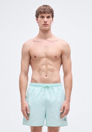 Menta zöld fürdőnadrág elasztikus derékpánttal és húzózsinórral. Bal lábán egy kis sötét logó található. Simább, könnyű anyagból készült.