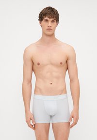Boxeri din bumbac gri, cu un talie moale etichetată "Hollister". Designul este ajustat, ajungând până la mijlocul coapsei, cu o textură netedă.