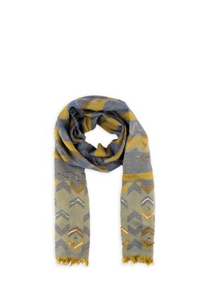 Lekki szalik z niebieskimi i musztardowo-żółtymi geometrycznymi wzorami oraz akcentami z cekinów, z frędzlami na końcach, luźno owinięty.