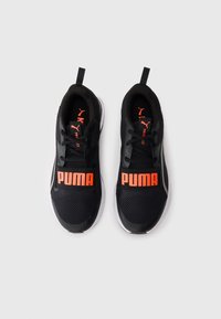 Adidași negri Puma cu logo-uri portocalii pe curele și pe limbă, cu tălpi albe și etichete de prindere, pe un fundal alb.
