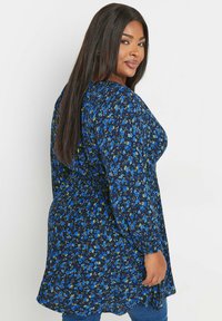 Sinekkimono siniseen kukkakuosiin, pitkät hihat ja ilmava malli. Pehmeä kangas, rento istuvuus ja kerätty yksityiskohta vyötäröllä.