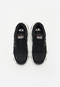 Black sneakers with mesh and suede materials, featuring a thick, beige sole and "DIESEL" branding on the tongue. Designed for comfort.