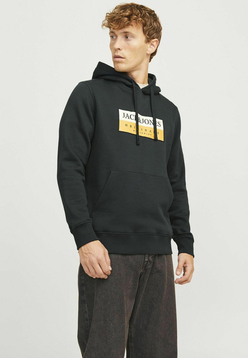 Schwarzer Hoodie aus weichem Stoff mit einer Fronttasche. Mit einem weißen und gelben Logo-Label auf der Brust. Einfaches Design, lässiger Schnitt.