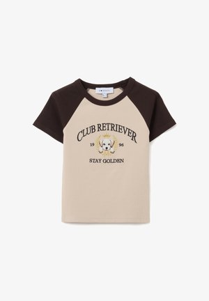 Kurzarm-T-Shirt mit beigem Körper und braunen Raglanärmeln. Es verfügt über gestickten Text und ein Grafik eines Hundes mit einer Krone und Lorbeeren.