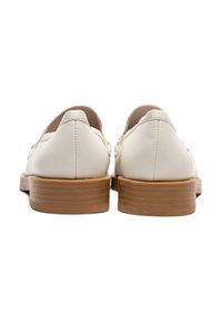 Valkoiset nahkakengät, joissa on sileä pinta ja matala puinen korko, pyöreä takaosa ja minimalistiset yksityiskohdat.