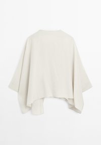 Poncho en lin léger beige, de forme rectangulaire lâche avec des manches larges ; il présente un col rond et un ourlet brut.