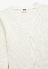 Witte gebreide cardigan met een V-hals, voorzien van ribbelboorden en drie witte knopen aan de voorkant. Gemaakt van zacht textielmateriaal.