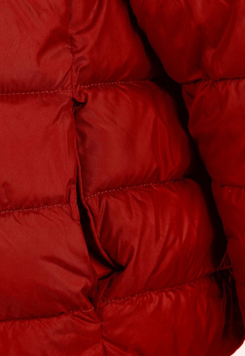 Czerwony ocieplany kurtka z gładką, błyszczącą teksturą, z pikowanymi sekcjami i widocznym przeszyciem. Materiał wydaje się lekki, ale jednocześnie ciepły.
