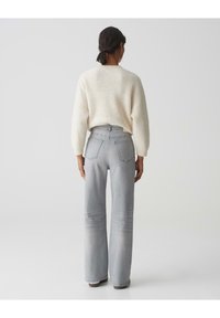 Grijze wijde jeans met een hoge taille en nette stiknaden, gecombineerd met een crèmekleurige, gestructureerde oversized gebreide trui.
