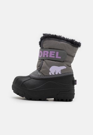 Botte d'hiver grise et noire pour enfant avec sangle violette "SOREL", logo d'ours polaire et doublure en fausse fourrure noire.
