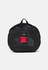 Black mesh duffel bag with round shape, featuring a red label displaying "BASE CAMP DUFFEL XXL" and a top carrying handle.