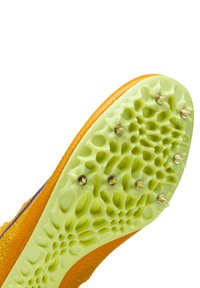 Chaussure de piste avec une tige jaune texturée et une semelle extérieure en caoutchouc vert. La semelle comporte plusieurs pointes métalliques pour améliorer l'adhérence.