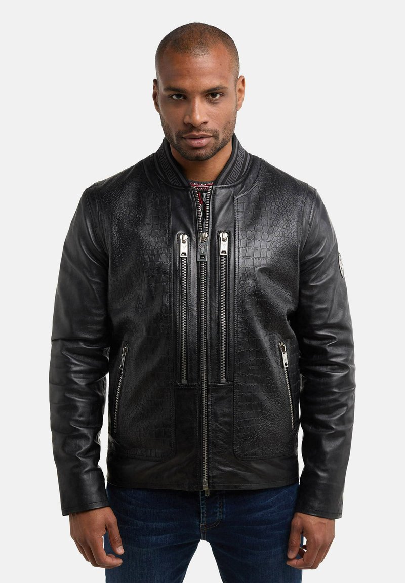 Veste bomber en cuir noir avec une finition texturée, dotée de deux poches zippées à l'avant et d'un col montant. Les fermetures éclair sont de couleur argentée.