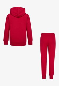 Haut à capuche rouge avec cordon de serrage et manches longues, associé à un pantalon de survêtement rouge assorti avec une taille élastique. Matière en coton.