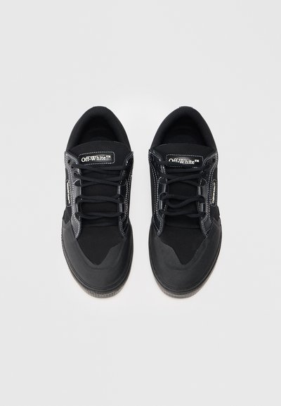 Para czarnych sneakersów Off-White z białymi szwami, sznurówkami i metkami z logo na języku oraz na boku, wyeksponowana na białym tle.
