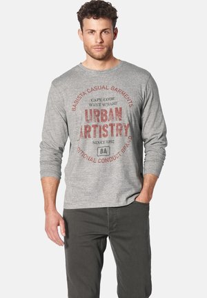 Graues langärmliges T-Shirt mit Rundhalsausschnitt, das einen roten grafischen Aufdruck mit der Aufschrift „Urban Artistry“ und graue Hosen mit strukturiertem Finish zeigt.