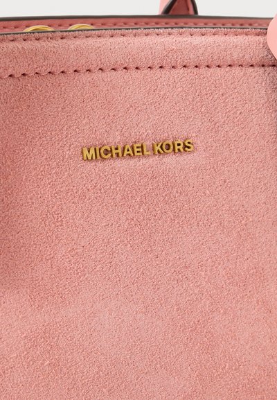Розов раздел от велурена чанта с надпис Michael Kors в златно и видимо шиене близо до горния ръб.