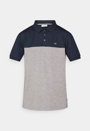 Tengerészkék és világosszürke színű, színblokkos pólóing, gallérral, három gombbal és CK logóval a mellkason. Puha, légáteresztő anyagból készült.