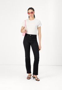Black jeans with a straight fit, high waist, and denim texture, paired with a white short-sleeve t-shirt and pink accessories.