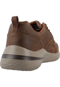 Zapatillas de deporte de cuero marrón con suela de goma, que presentan un cuello acolchado, una puntera texturada y una franja de acento marrón y gris en la suela.