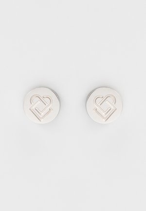 Paired de boutons de manchette ronds en argent avec un dessin gravé de cœur entrelacé et un motif géométrique sur un fond clair.